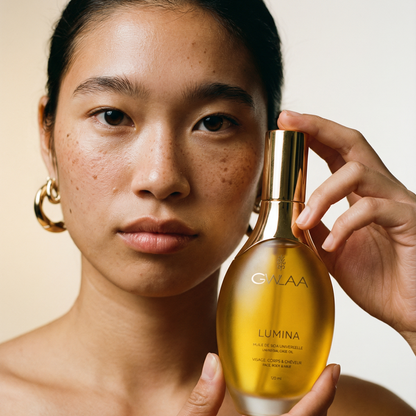 Modèle peau medium tenant le flacon Lumina de GWLAA, huile de soin universel nourrissante pour le visage, le corps et les cheveux.